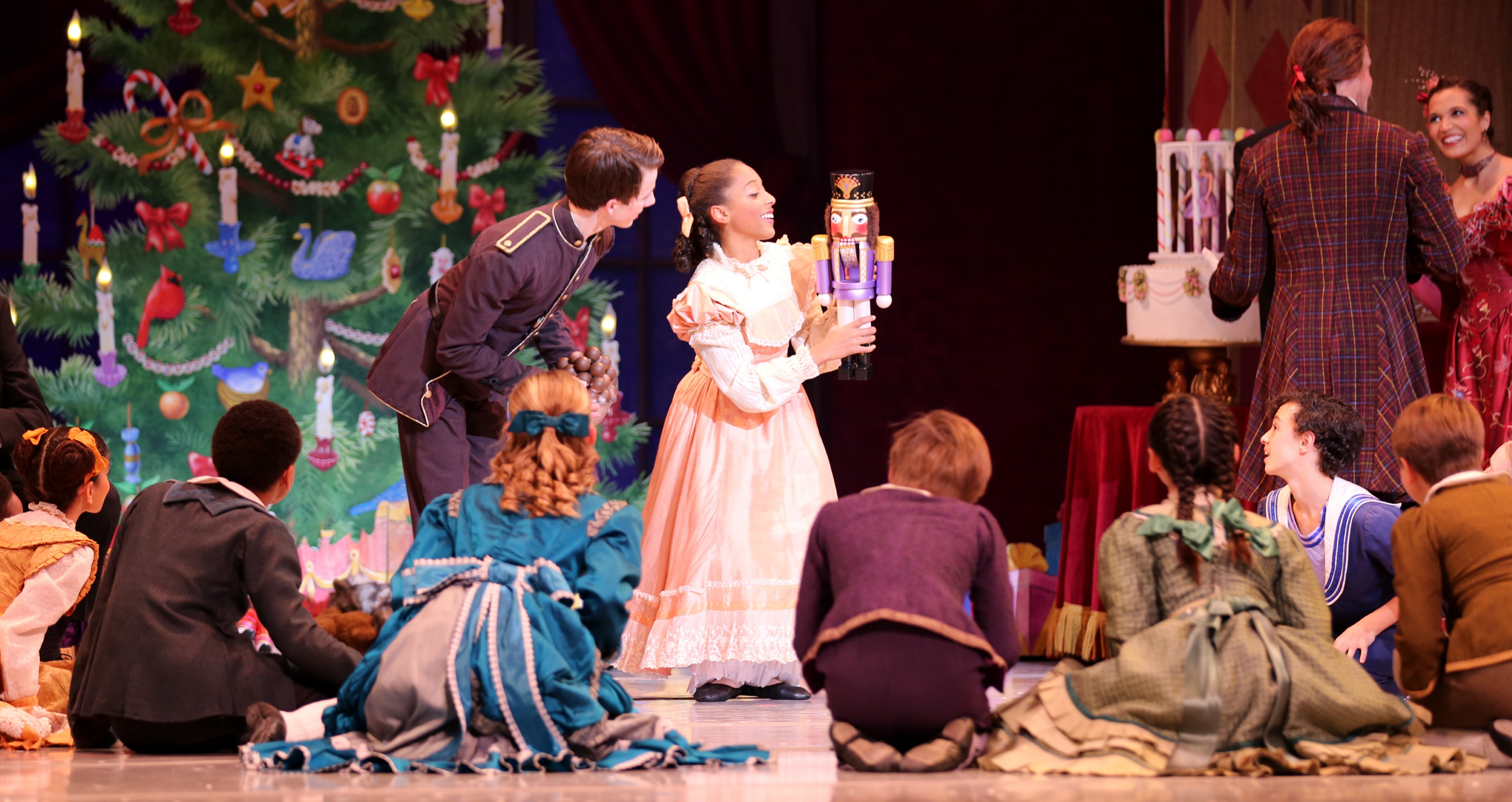 Actors on stage with a woman holding anutcracker